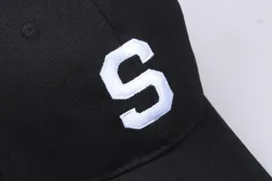 Gros plan sur la broderie blanche lettre S sur une casquette de baseball en coton noir