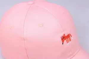 Detailansicht der rosa Baumwoll-Basecap mit orangefarbener Fuchssticker und Ösen
