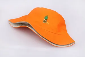 Detalle de un gorro de pescador naranja reversible con bordado de piña y texto Pin