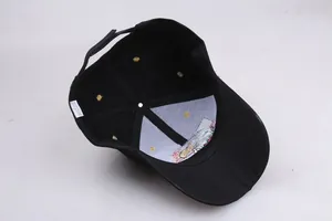 Interior detail of black cotton baseball cap showing 6-panel structure and washing label