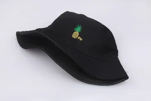 Bordado detallado de una piña amarilla y texto Pin en un sombrero de pescador negro
