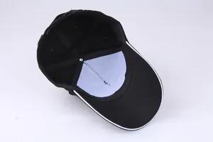 Inside detail of 5-panel black cotton baseball cap showing internal lining and white brim piping