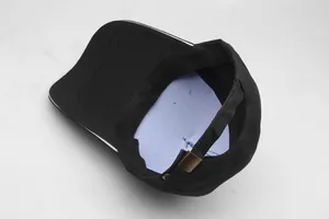 Detail view of black baseball cap showing the adjustable metal buckle and blue inner lining