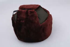 Detail of dark green winter trapper hat featuring thick reddish-brown faux fur lining