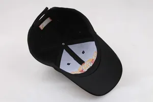 Detail of black baseball cap interior with fine stitching and gold embroidered logo