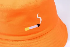 Close-up of bright orange bucket hat featuring cigarette embroidery and cotton texture