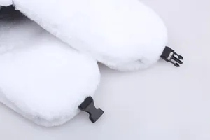 Close-up of white faux rabbit fur ear flaps with a black plastic buckle for secure fastening