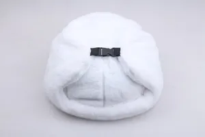 Detail of white faux fur trapper hat featuring adjustable black nylon straps and buckle