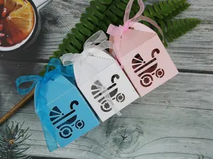 Detailed laser-cut baby carriage candy boxes in pink, white, and blue with ribbons