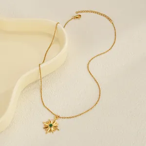 Titanium steel gold necklace with starburst pendant and green stone on decor tray