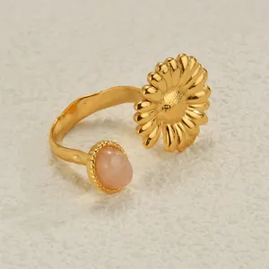 Macro detail of gold-plated open ring featuring a pink stone and daisy flower design