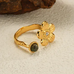 Macro view of gold-plated bypass ring with green gemstone and floral zircon detail