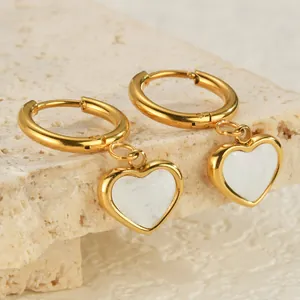 Detailed close-up of 18K gold plated heart earrings with white shell inlay on stone