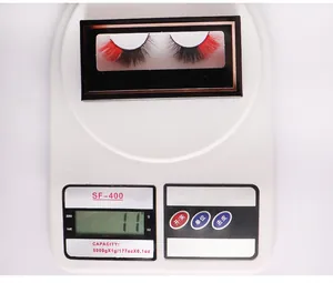 Détail de faux cils volumineux noir et rouge sur une balance indiquant 11g