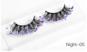 Macro view of artistic false eyelashes with purple hexagonal glitter on a clear tray