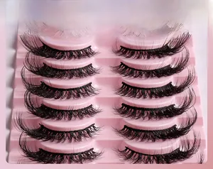 Macro detail of seven pairs of layered black 3D volume faux mink eyelashes on pink tray
