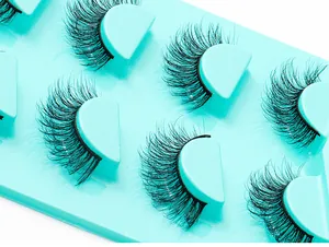 Vue macro détaillée de faux cils noirs denses et bouclés sur un plateau vert menthe