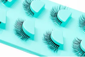 Détails de 4 paires de faux cils volumineux et recourbés sur plateau vert vif