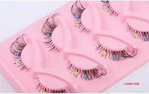 Detail of 5 pairs of fox-style false eyelashes with tiny colorful flower sequins on a pink tray
