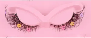 Macro detail of false eyelashes with colorful flower sequins on a pink tray