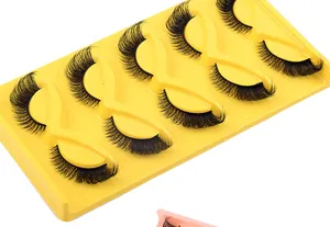 Detail of 5 pairs of thick 3D fox-eye eyelashes on a yellow curved plastic tray