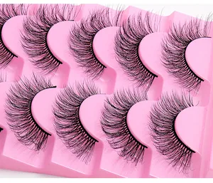 Détail de 8 paires de faux cils noirs multicouches et bouclés sur un plateau rose