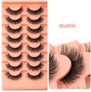Gros plan de 8 paires de faux cils volumineux et recourbés sur un plateau rose chic
