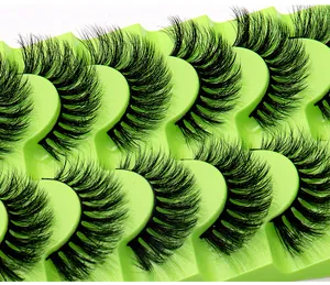 Gros plan de 8 paires de faux cils 3D épais sur un plateau de présentation vert vif