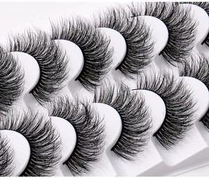 Vue macro de faux cils denses et bouclés disposés sur un plateau blanc de 8 paires