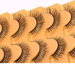 Gros plan de faux cils en vison synthétique sur plateau jaune montrant un volume intense
