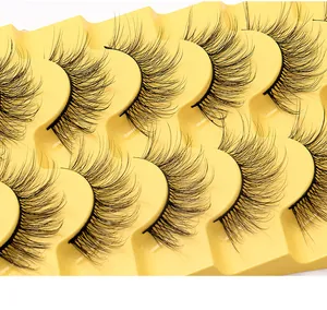 Gros plan de 8 paires de faux cils volumineux et recourbés sur un plateau jaune vif