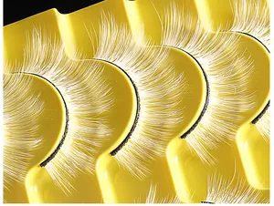 Macro-opname van 10 paar witte valse wimpers met zwarte wortels op een geel blad