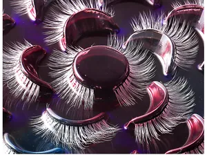 Macro view of dense white feather-like false eyelashes on a purple tray for stage makeup