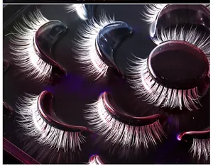 Macro detail of white long-curved false eyelashes in a purple tray for festival makeup