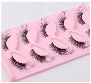 Detail of 5 pairs of faux eyelashes with colorful pearl accents on a pink tray