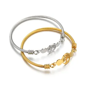 Detail of gold and silver steel cable bracelets with tree of life charms on white background