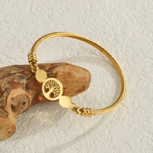 Gold stainless steel wire cable cuff bracelet featuring a hollow Tree of Life charm