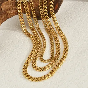 Gold plated stainless steel Cuban link chains displayed on rustic wood over white surface