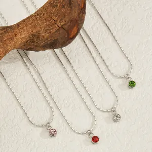 Colliers en acier inoxydable avec pendentifs pierre de naissance colorés sur bois naturel