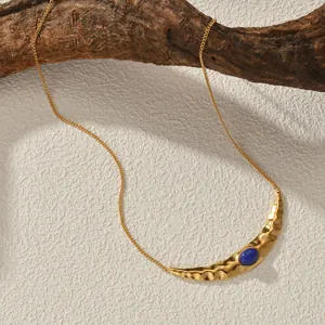 Vintage textured gold moon necklace with lapis lazuli pendant on a rustic branch