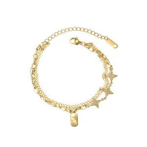Detail of layered gold stainless steel bracelet featuring star pendants and etched tag