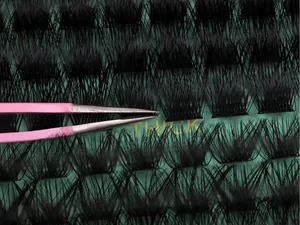Macro shot of thick DIY cluster lashes with tweezers on a green striped packaging card