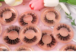 Dettaglio di ciglia finte folte e ricce in scatole tonde con base glitterata rosa