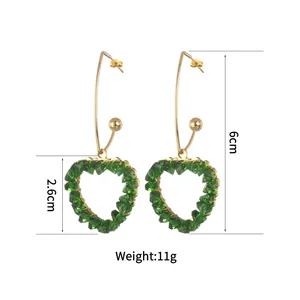 Detail view of heart-shaped green crystal earrings showing 6cm length and 11g weight