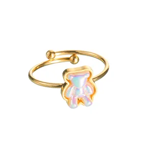 Macro shot of gold adjustable ring featuring a pearlescent bear charm on white background