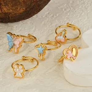 Detail of five colorful enamel rings with butterfly and star motifs on white texture