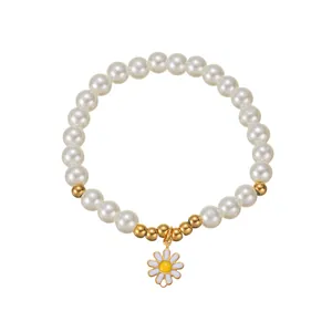 Vue détaillée du bracelet de perles blanches avec pendentif marguerite doré