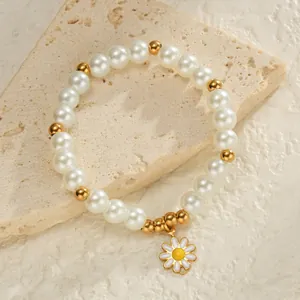 Gros plan d'un bracelet en perles avec perles dorées et breloque marguerite sur pierre