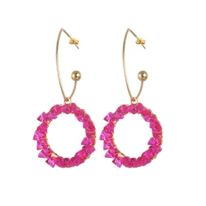 Golden hook earrings with magenta faceted crystal bead charms in a circular design