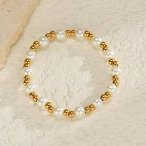 Détail des perles dorées à l'or 18K et perles blanches sur le bracelet élastique